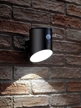 Black outdoor wall light with motion sensor on a brick wall